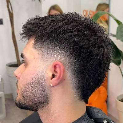A man with a short mullet hairstyle, featuring a faded undercut on the sides with textured, spiky hair on top and a slightly longer back, offering a modern twist on the classic mullet.