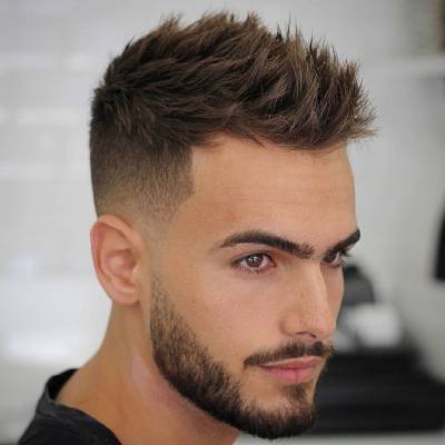 A man with an undercut hairstyle, featuring short faded sides and a textured, spiked top with a clean beard, giving a bold and stylish appearance.