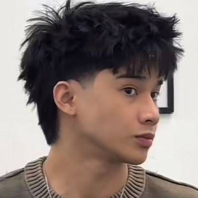 A side profile of a man with a faded mullet, featuring a fringe at the front and short sides.