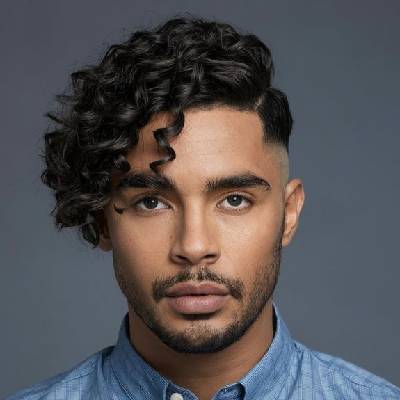  A man with side-parted curly hair, showcasing defined curls on top and a clean fade on the sides for a sharp and stylish look.