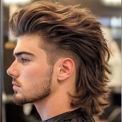 geschnitten, während das Haar am Hinterkopf lang und voluminös ist. Der Mann trägt einen gepflegten Bart und sieht in einem modernen, stylischen Friseur-Look aus.